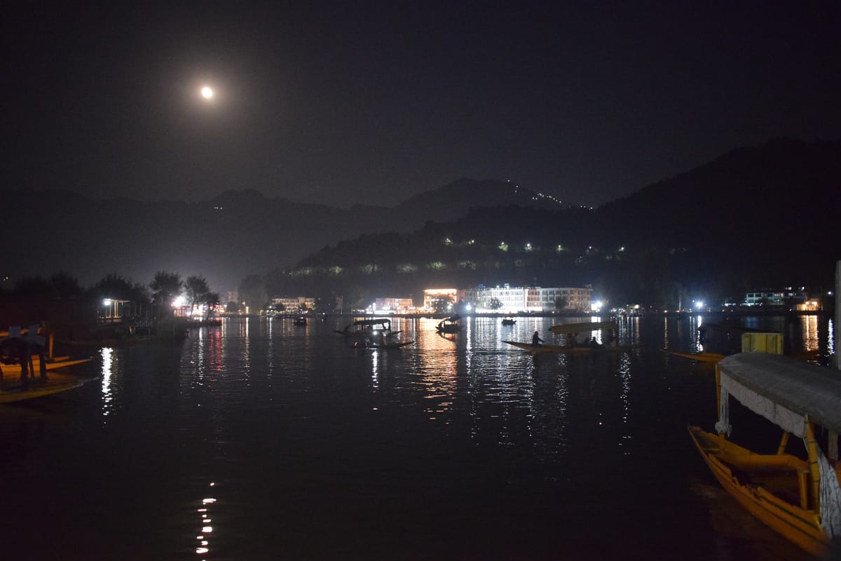 Moonlight and lights reflected on Dal Lake at night